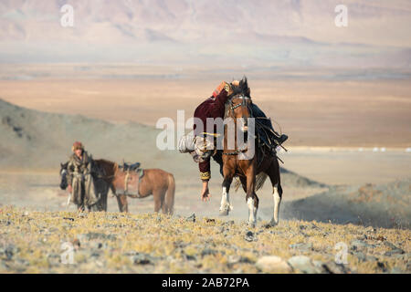 Jeu mongole traditionnelle où un cavalier sur l'objectif d'aller chercher une serviette depuis le sol à pleine vitesse au galop. Ulgii, la Mongolie. Banque D'Images