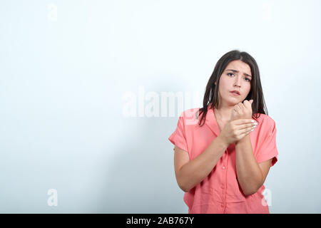 Plate caucasian young woman in pink shirt faisant massage sur les mains, à la triste Banque D'Images