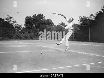 Début des années 1900 - Vintage tennis tennis player sauter et frapper une balle sur le court de tennis ca. 1915-1923 Banque D'Images