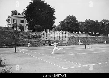 Début des années 1900 - Les joueurs de tennis sur un court de tennis avec club house en arrière-plan ca. 1915-1923 Banque D'Images