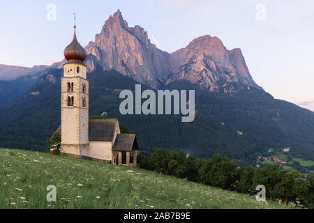 Paysages de Sunrise Eglise Saint Valentin sur une colline herbeuse avec vue sur pics accidentés de la montagne Schlern avec alpenglow en arrière-plan dans la vallée o Banque D'Images