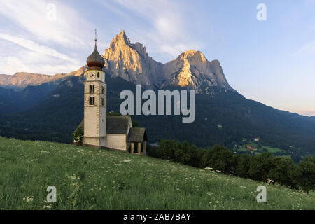 Paysages de Sunrise Eglise Saint Valentin sur une colline herbeuse avec vue sur pics accidentés de la montagne Schlern avec alpenglow en arrière-plan dans la vallée o Banque D'Images