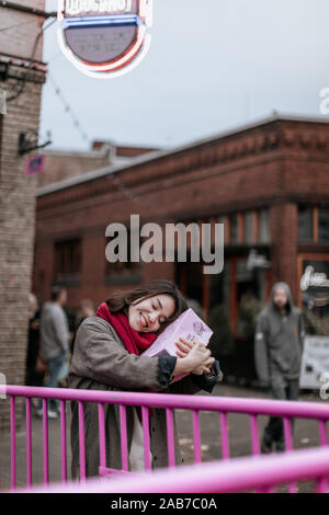 Portland, Oregon - Nov 16, 2019 : Asian female traveler holding Voodoo donuts fort dans le centre-ville de Portland Banque D'Images