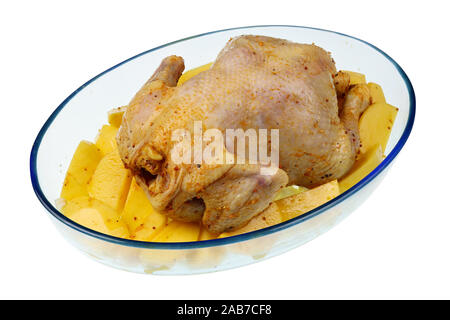 Miel et gingembre mariné le poulet cru se trouve sur les tranches de pommes de terre dans un verre résistant à la chaleur au four. Isolated on white studio food shot Banque D'Images