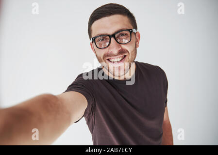 Jeune hipster guy portant des lunettes rire heureusement isolé sur fond blanc Banque D'Images