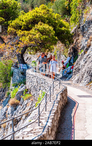 Positano, Italie - Septembre 05, 2019 : promenade pittoresque sur le bord de rocky mountain et la mer Tyrrhénienne dans la baie de Positano. Les gens à monter et descendre e Banque D'Images