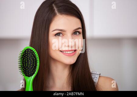 Girl est titulaire d'une brosse sans cheveux et souriant Banque D'Images