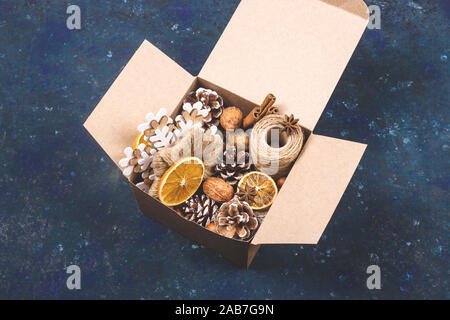 Boîte en carton kraft eco avec zéro déchets décorations pour Noël et Nouvel An avec les cônes, les noix, les oranges et de la ficelle. Banque D'Images