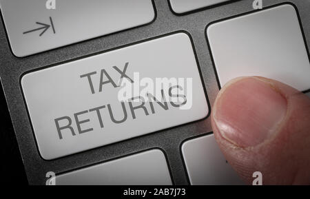 Un homme en appuyant sur une touche du clavier d'un ordinateur avec les mots d'impôt. Les déclarations de revenus en ligne concept image. Banque D'Images