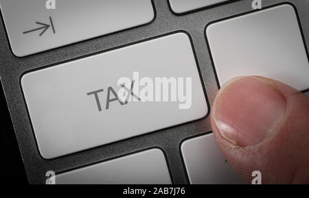 Un homme en appuyant sur une touche du clavier d'un ordinateur avec le mot taxe. Les déclarations de revenus en ligne concept image. Banque D'Images