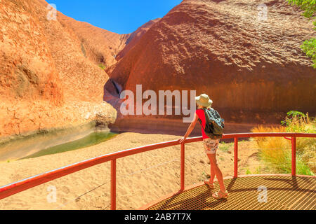 Femme de tourisme avec large hat standing au balcon en admirant Mutitjulu Waterhole, Parc National d'Uluru-Kata Tjuta, UNESCO, Territoire du Nord, Australie Banque D'Images