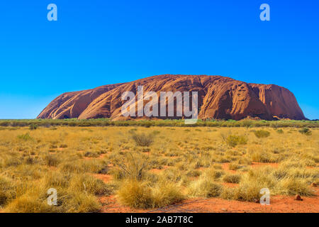 Sable rouge de l'Outback australien à Ayers Rock en saison sèche, immense monolithe de grès dans le Parc National d'Uluru-Kata Tjuta, l'UNESCO, de l'Australie Banque D'Images