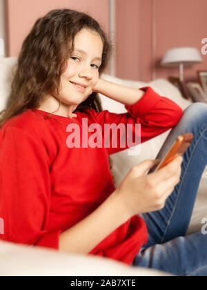 Ein junges Maedchen auf dem canapé, mit einem Mobiltelefon in der Hand Banque D'Images