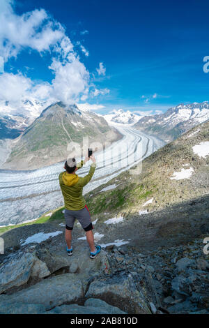 Vue arrière du Glacier d'Aletsch man photographing with smartphone d'Eggishorn viewpoint, Alpes Bernoises, canton du Valais, Suisse, Europe Banque D'Images
