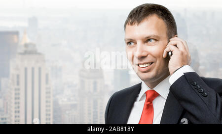 Un Geschaeftsmann, der ein Mobiltelefon in der Hand haelt Banque D'Images