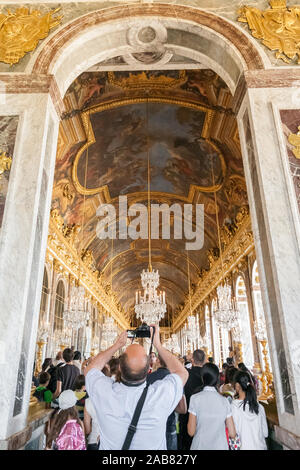 Grande vue portrait d'un homme dans la salle debout à l'entrée voûtée de la célèbre Galerie des Glaces et faire des photos de la belle peint... Banque D'Images