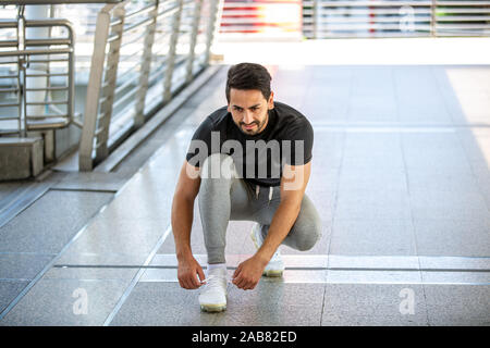 Fitness, sport, exercice et mode de vie - deux homme mix-race dans les vêtements de sport et vous détendre assis sur l'étirement de la jambe sur l'étape de stadium Banque D'Images