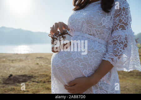 Portrait of pregnant woman holding baby shoe extérieur permanent Banque D'Images