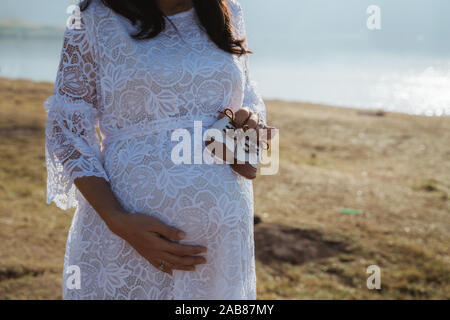 Portrait of pregnant woman holding baby shoe extérieur permanent Banque D'Images