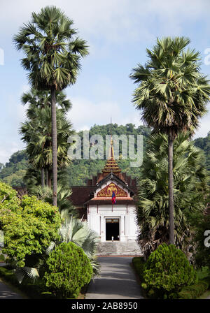 Route droite pour le blanc Palais Royal de Luang Prabang, bordée de grands palmiers sur une journée ensoleillée de septembre. Banque D'Images