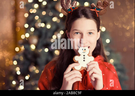 Happy girl tenir bonhomme de pain d'épices. concept de célébration de Noël et la cuisine. Enfant en chapeau de Père Noël la veille de Noël. Croire en miracle de Noël. Banque D'Images