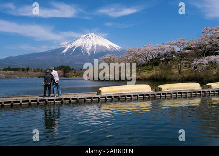 Le Japon, Fujinomiya, préfecture de Shizuoka : Le Mont Fuji avec son sommet enneigé vu du lac Tanuki. Couple de touristes japonais sur un ponton d'oeil Banque D'Images