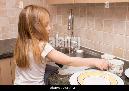 Jeune enfant lave jusqu'à l'évier de cuisine, tâches domestiques Banque D'Images