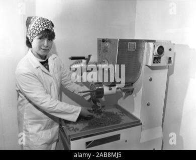 Années 1980, historique, une travailleuse en salopette et foulard, utilisant une machine italienne dans une usine alimentaire, pour faire des pâtes, fusilli, Yorkshire, Angleterre, ROYAUME-UNI. Banque D'Images