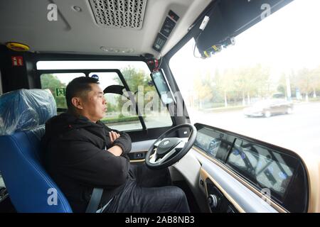 Un superviseur de sécurité chinois a les bras croisés sur la chese pendant qu'il observe la situation sur un 5G en fonctionnalités de conduite auto-minibus sur la route en cours d'exécution Banque D'Images