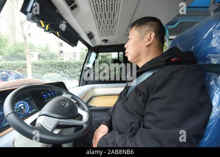 Un superviseur de sécurité chinois a les bras croisés sur la chese pendant qu'il observe la situation sur un 5G en fonctionnalités de conduite auto-minibus sur la route en cours d'exécution Banque D'Images