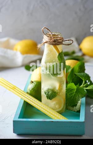 Boisson froide d'été avec les citrons, les feuilles de menthe, la chaux dans une bouteille de verre, près de les ingrédients pour faire de la limonade.