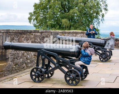 Famille avec le père et les enfants jouant sur les vieux canons d'artillerie ou d'armes à feu sur la grande batterie, le château de Stirling, Scotland, UK Banque D'Images