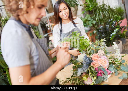 Deux jeunes fleuristes en formation en nouant un bouquet Banque D'Images