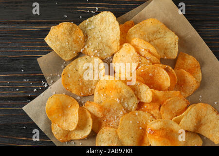Croustilles de pommes de terre avec du sel et du papier craft sur fond de bois, vue du dessus Banque D'Images