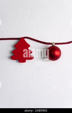 Arbre rouge et bois d'ornement de Noël Boule accroché sur corde sur le ciment blanc ball Banque D'Images