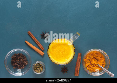 Mise à plat avec le curcuma ayurvédique latte, cannelle, cardomom sur un fond bleu foncé. Copy space Banque D'Images