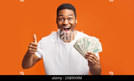 Heureux homme noir de la détention de monnaie sur fond orange Banque D'Images Heureux homme noir de la détention de monnaie sur fond orange Banque D'Images