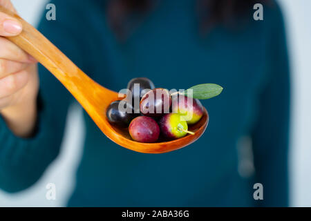 Une femme poignée d'olives de la Méditerranée sur une cuillère en bois Banque D'Images