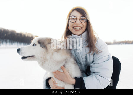 Jeune fille jouant avec un chien husky de Sibérie dans winter park. Ils marchent sur un lac gelé Banque D'Images