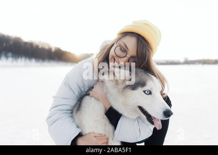 Jeune fille jouant avec un chien husky de Sibérie dans winter park. Ils marchent sur un lac gelé Banque D'Images