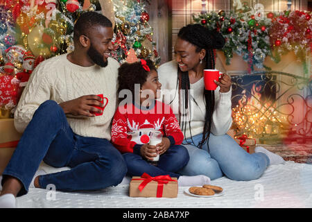 La famille afro joyeuse boire du lait et manger des biscuits, célébrer Noël ensemble Banque D'Images