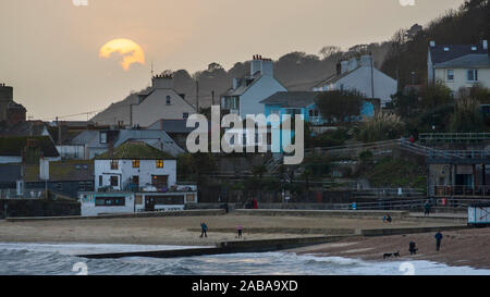 Lyme Regis, dans le Dorset, UK. 26 Nov, 2019. Météo britannique. Le soleil partiellement obscurci par de gros nuages au-dessus de la mer au coucher du soleil à Lyme Regis dans le Dorset à la fin d'un jour de tempête et ciel couvert. Crédit photo : Graham Hunt/Alamy Live News Banque D'Images