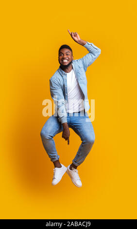 Black guy sautant dans l'air, pointant vers le haut et vers le bas avec les mains Banque D'Images