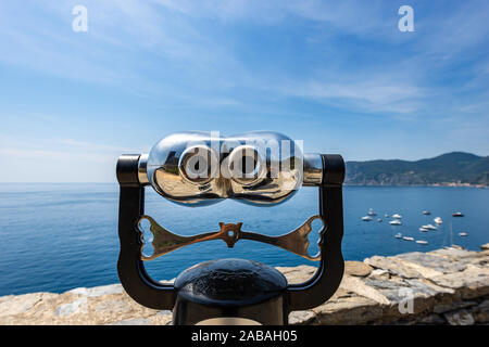 Jumelles électroniques fonctionnant avec des pièces pour les touristes sur un paysage marin floue avec les bateaux. Vernazza village, Parc National des Cinque Terre, en Ligurie, Italie Banque D'Images