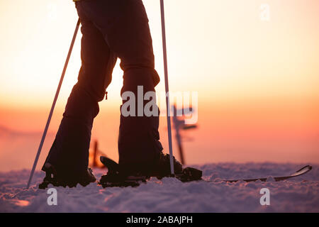 La photo en gros plan de skieuses jambes avec des bâtons de ski contre sunset sky Banque D'Images