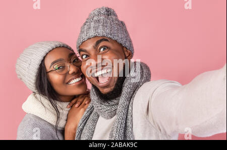 Couple afro joyeuse de prendre des vêtements d'hiver en selfies Banque D'Images