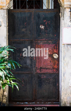 Une vieille porte en métal noir rusy trouvés dans une ruelle latérale retour à Hanoi, Vietnam Banque D'Images