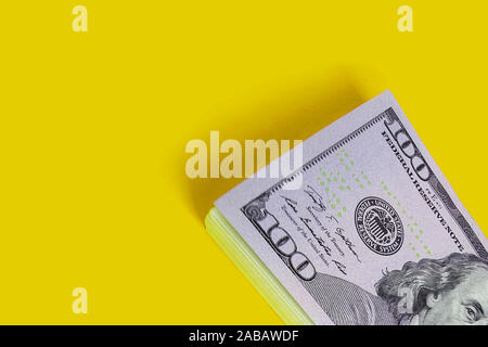 Pile de centaines de dollars isolé sur fond jaune avec copyspace Banque D'Images