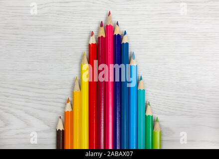 Série de crayons de couleur sur un fond de bois blanc placés de manière à dessiner une courbe graphique Banque D'Images