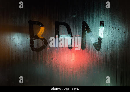 Le mot écrit sur l'interdiction de vitre de fenêtre humide nuit close-up avec l'arrière-plan flou. Banque D'Images